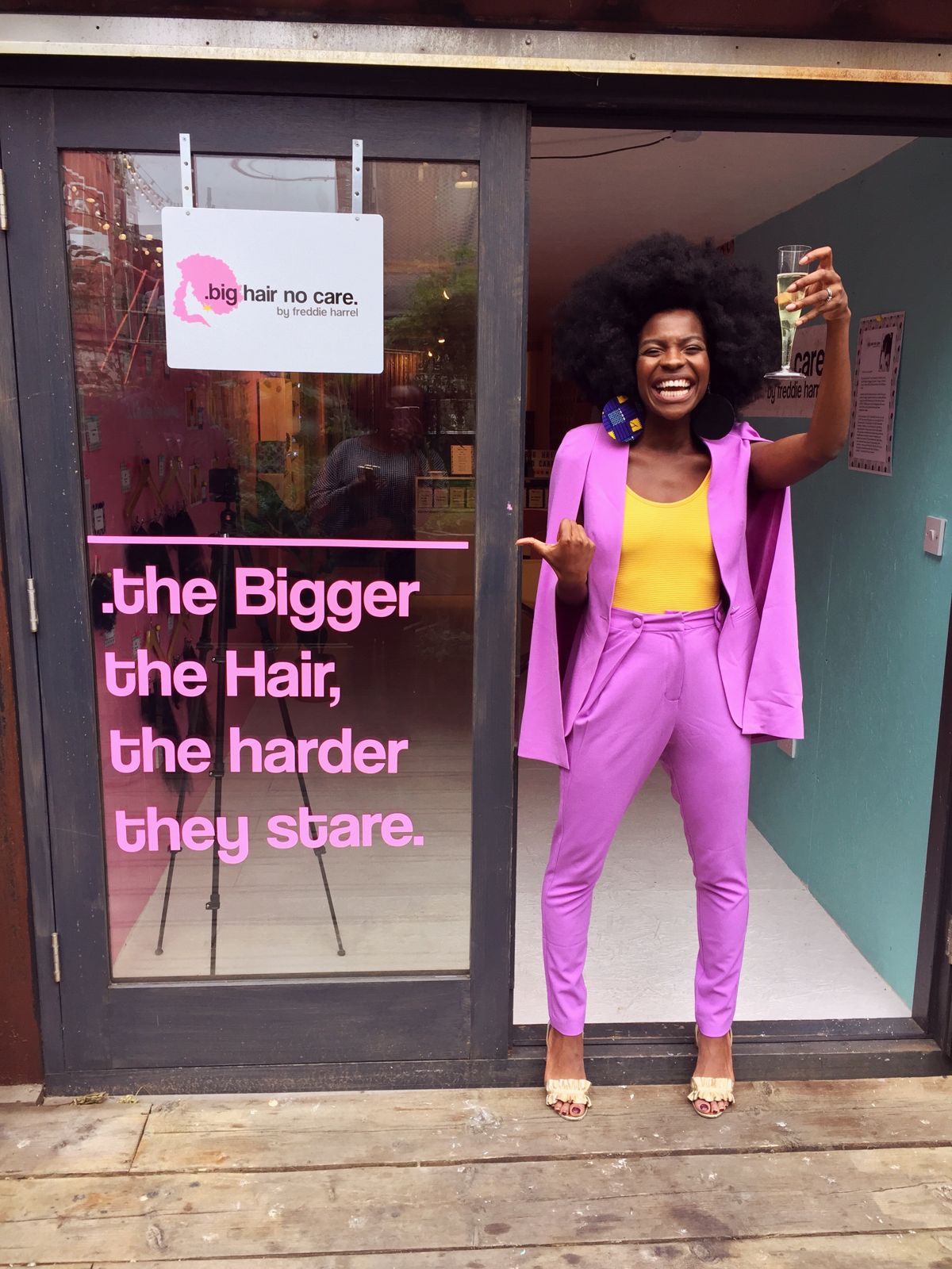 Freddie raising a glass in a pink suit at a Big Hair No Care pop-up
