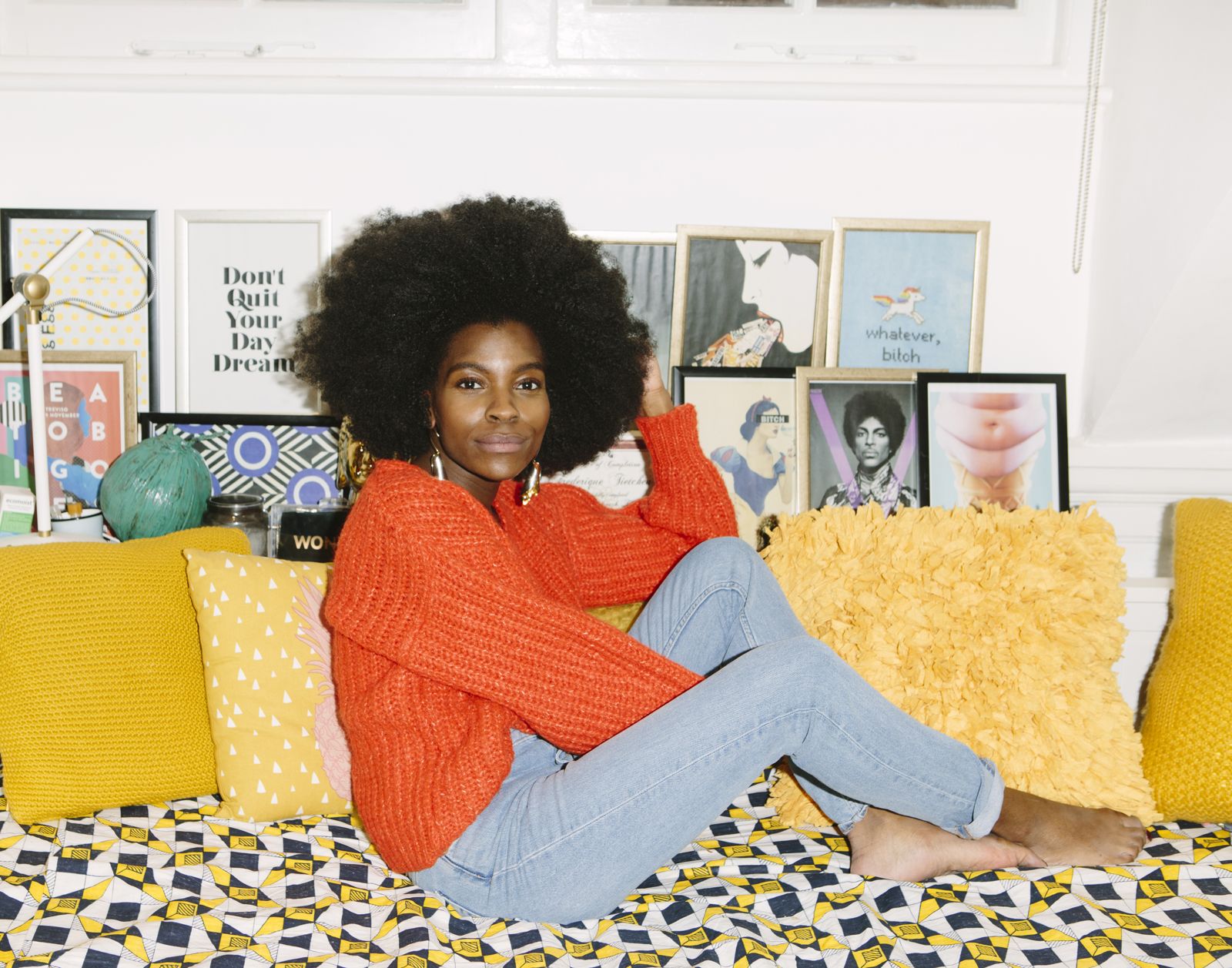Freddie in an orange jumper sitting cross-legged on a sofa